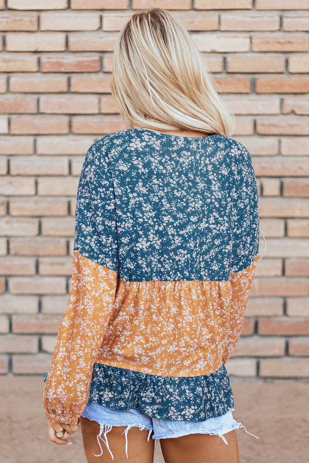 Orangefarbene Bluse mit Blumenmuster, Farbblockdesign, Rüschensaum und Rundhalsausschnitt
