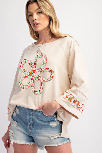 Beiges Oberteil mit Blumen-Patch-Grafik, sichtbaren Nähten und weiten Ärmeln