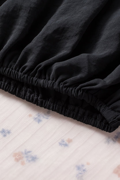 Schwarze, plissierte, lockere Bluse mit gepolsterten Schultern und geknöpften Manschetten