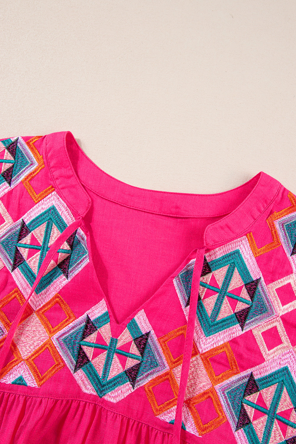 Erdbeerrosa Bluse mit V-Ausschnitt und geometrischer Stickerei, Quaste und Schleife