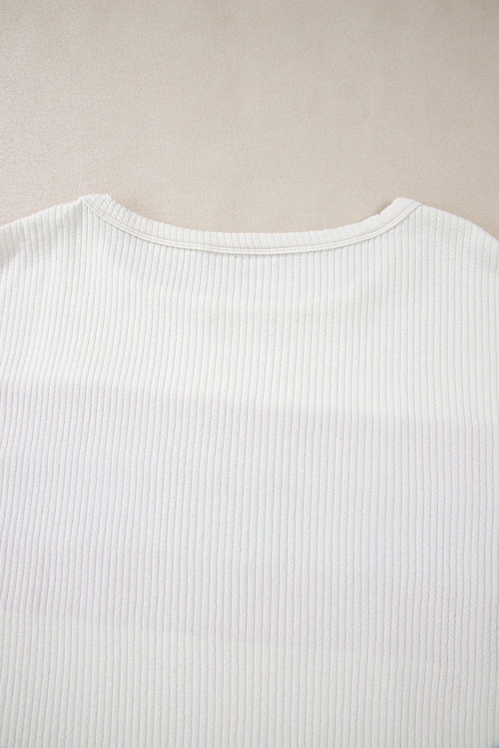 Weißes Stricktop mit Patchwork-Muster und sichtbaren Nähten sowie langen Ärmeln