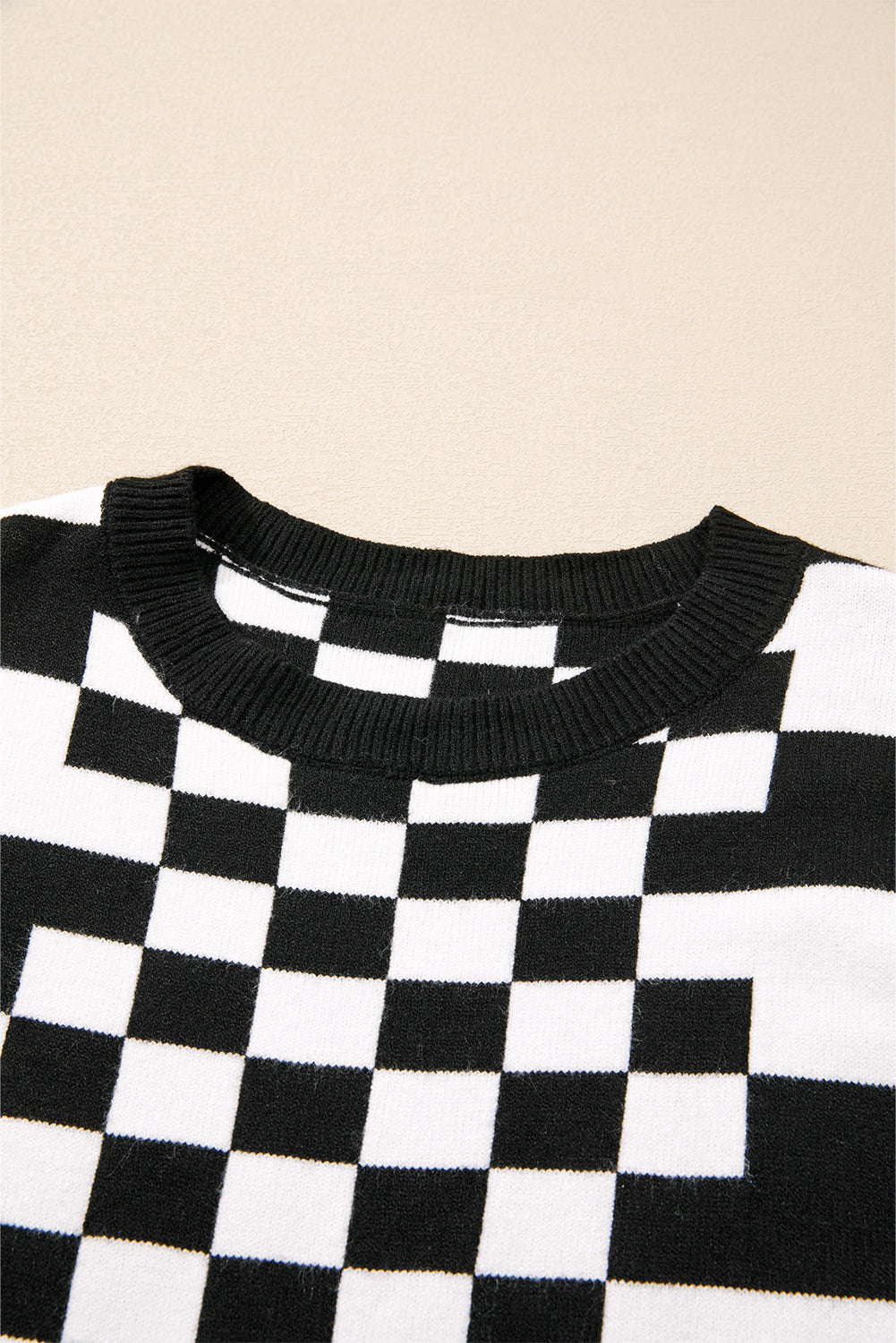 Schwarzer Pullover mit Karomuster und überschnittener Schulterpartie und Rundhalsausschnitt