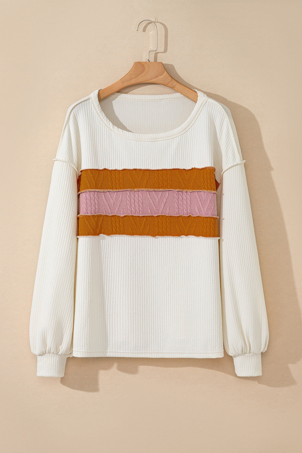Weißes Stricktop mit Patchwork-Muster und sichtbaren Nähten sowie langen Ärmeln