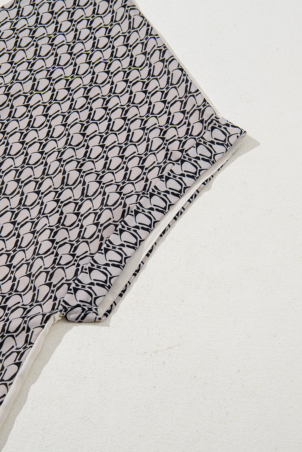 Haferflockenfarbenes Patchwork-Oberteil mit V-Ausschnitt und geometrischem Kontrastdruck in Übergröße