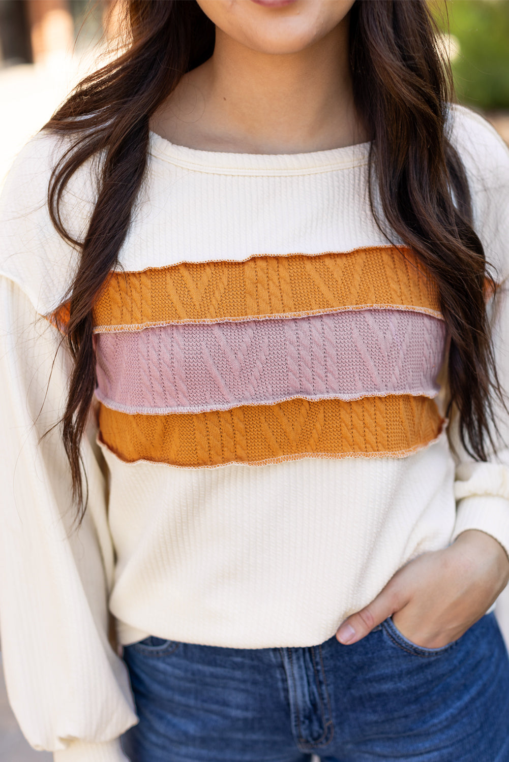 Weißes Stricktop mit Patchwork-Muster und sichtbaren Nähten sowie langen Ärmeln