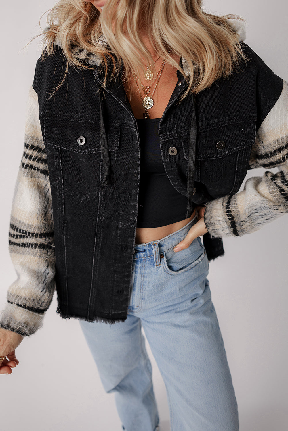 Schwarze Jeansjacke mit Kapuze und karierten Ärmeln und ausgefranstem Saum