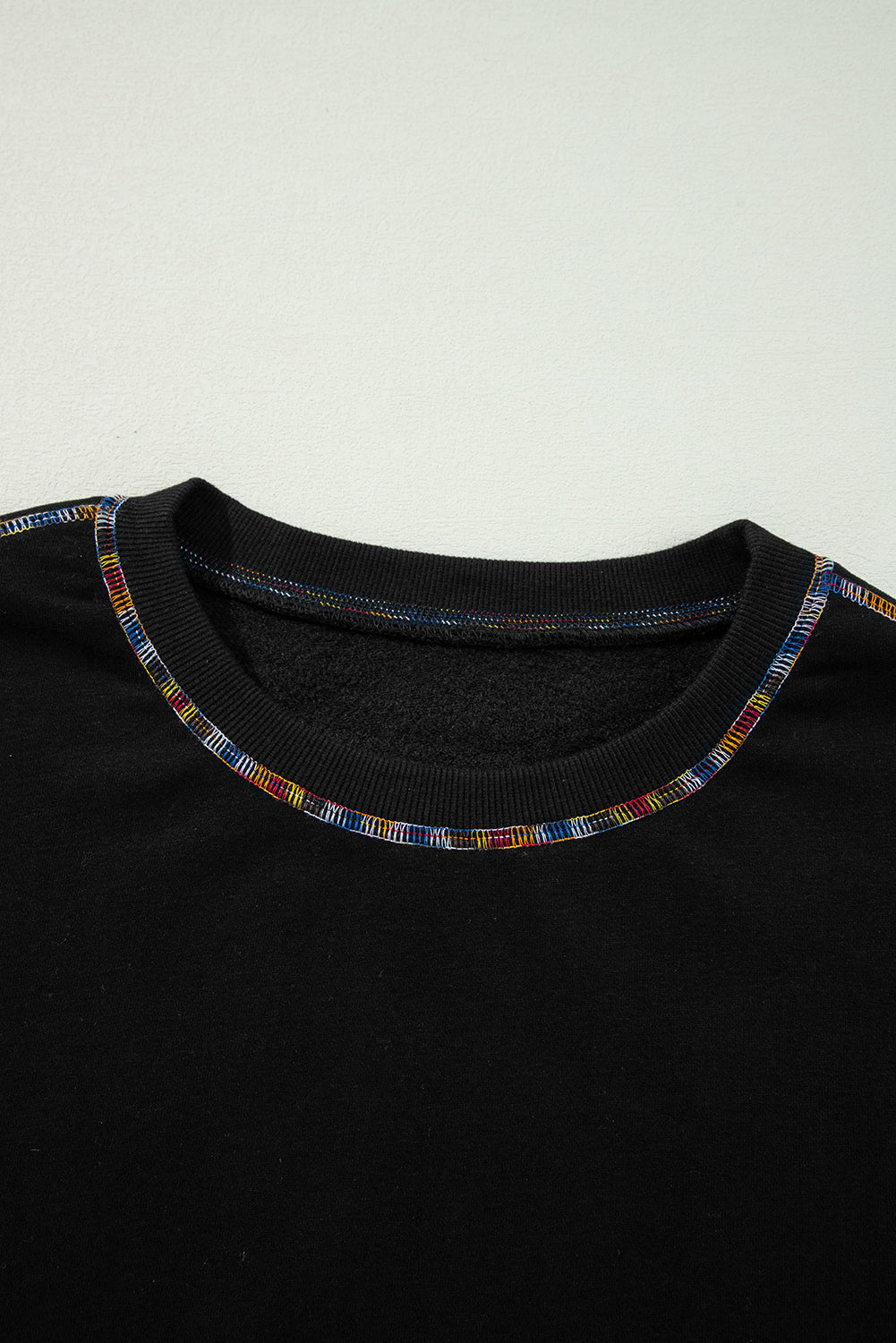 Schwarzes Pullover-Sweatshirt mit überschnittener Schulter und kontrastierendem Regenbogenbesatz