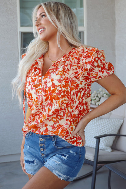 Orangefarbene Bluse mit Blumenmuster, Rüschen, kurzen Puffärmeln und Schlitz am Hals