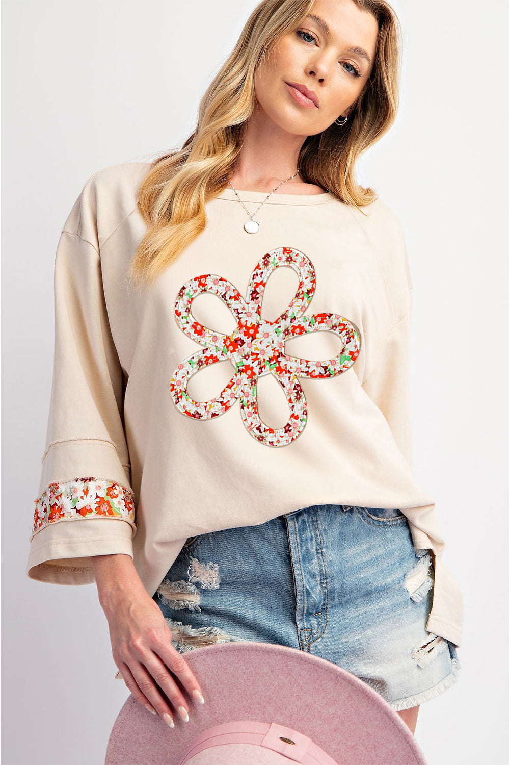Beiges Oberteil mit Blumen-Patch-Grafik, sichtbaren Nähten und weiten Ärmeln