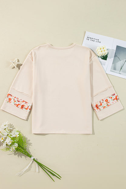 Beiges Oberteil mit Blumen-Patch-Grafik, sichtbaren Nähten und weiten Ärmeln
