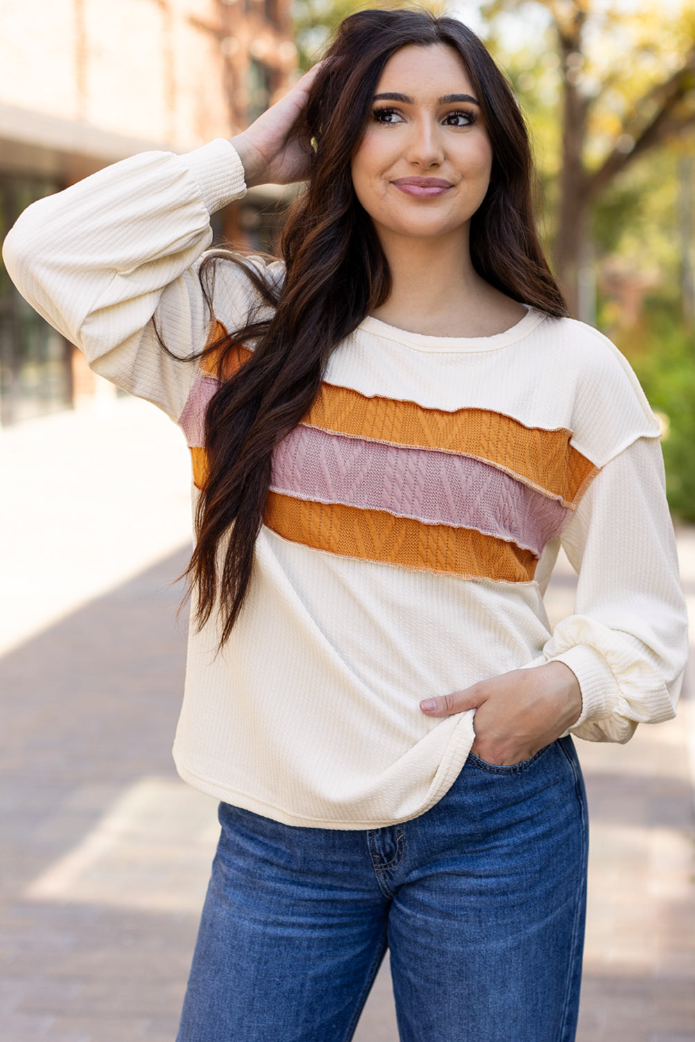 Weißes Stricktop mit Patchwork-Muster und sichtbaren Nähten sowie langen Ärmeln