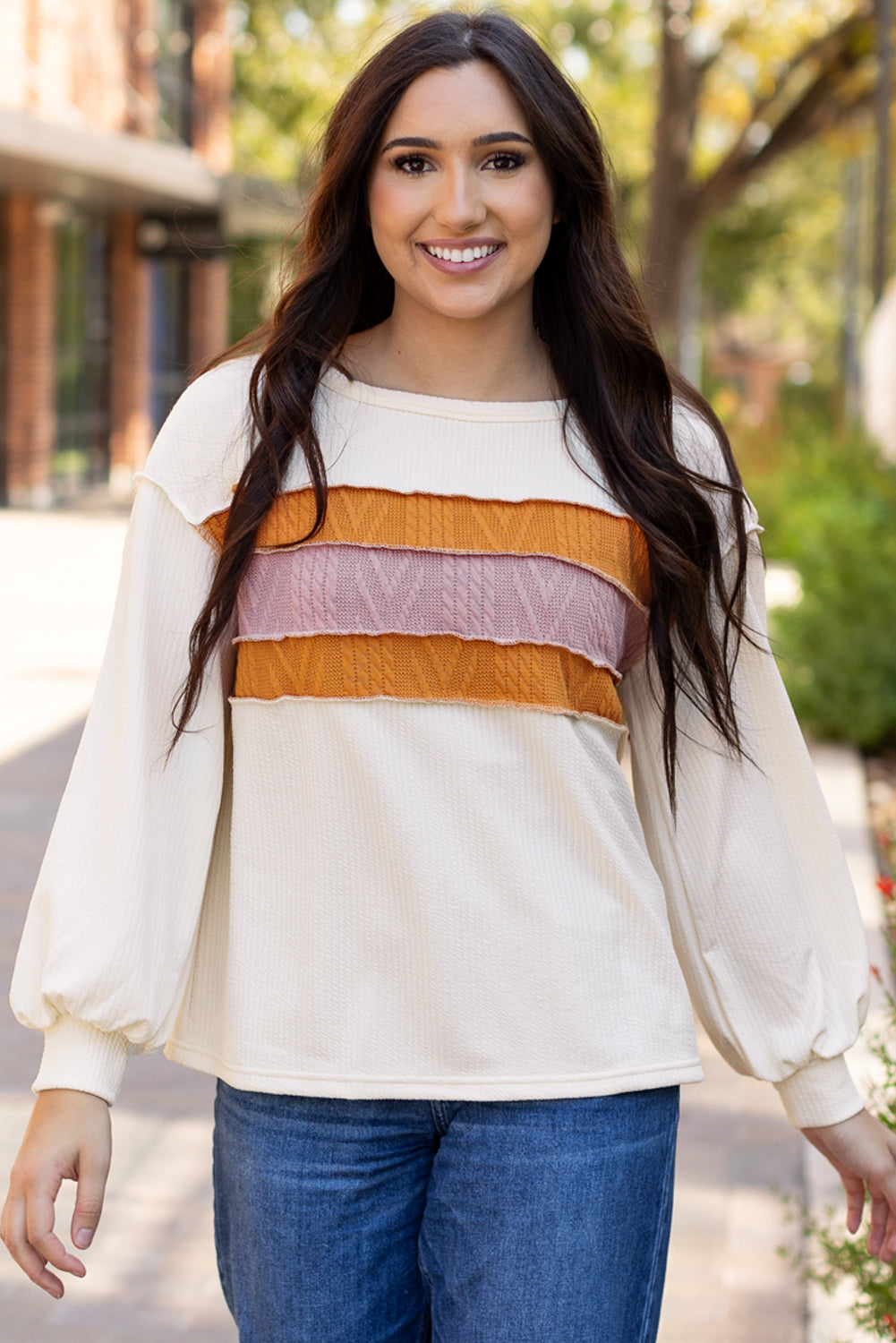Weißes Stricktop mit Patchwork-Muster und sichtbaren Nähten sowie langen Ärmeln