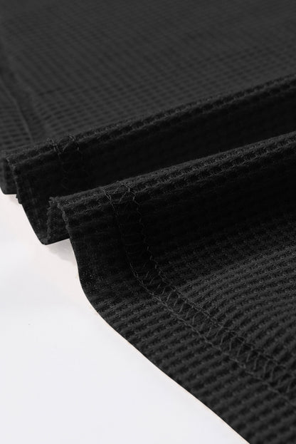 Schwarzes, langärmliges Oberteil aus Waffelstrick mit Knöpfen