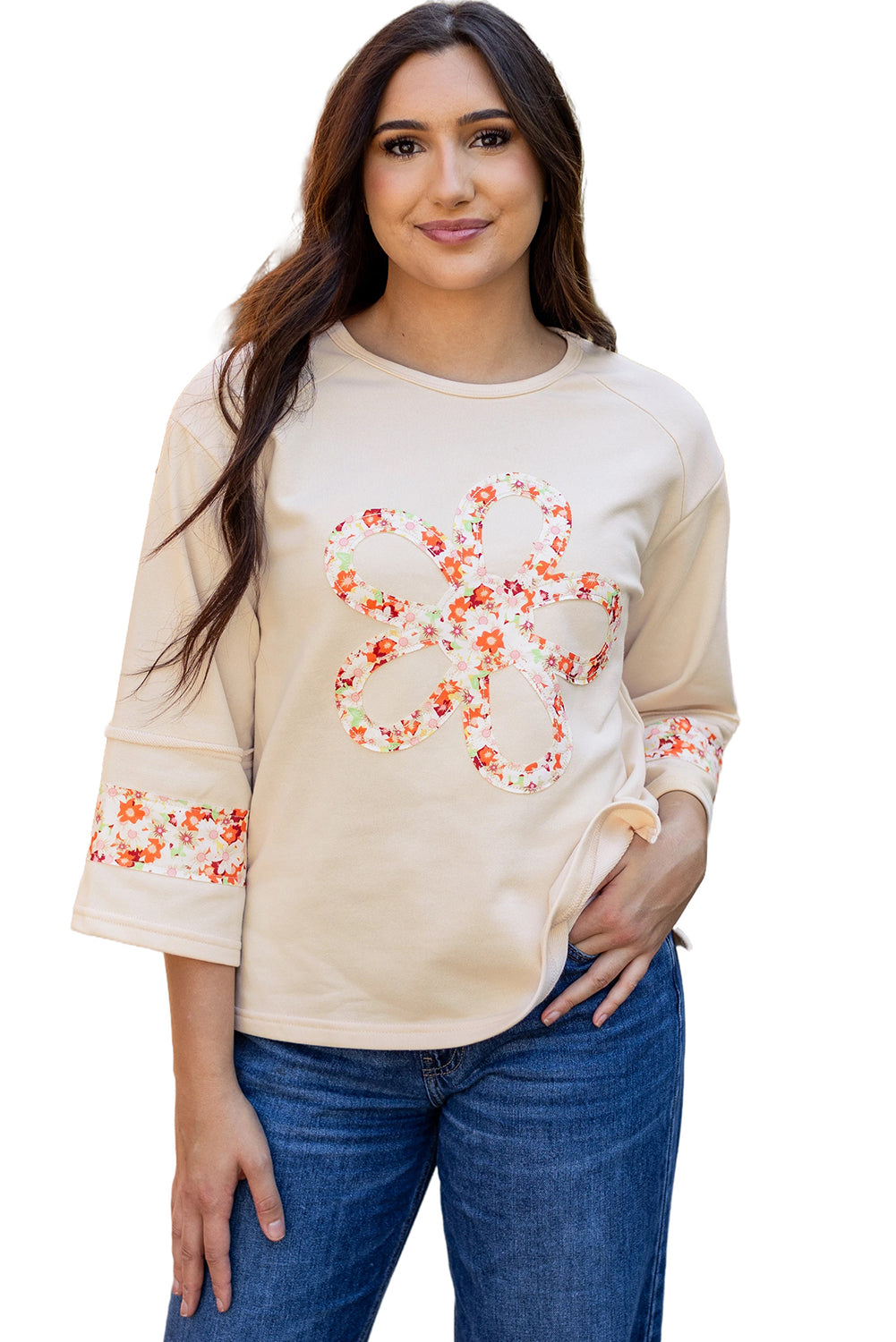 Beiges Oberteil mit Blumen-Patch-Grafik, sichtbaren Nähten und weiten Ärmeln