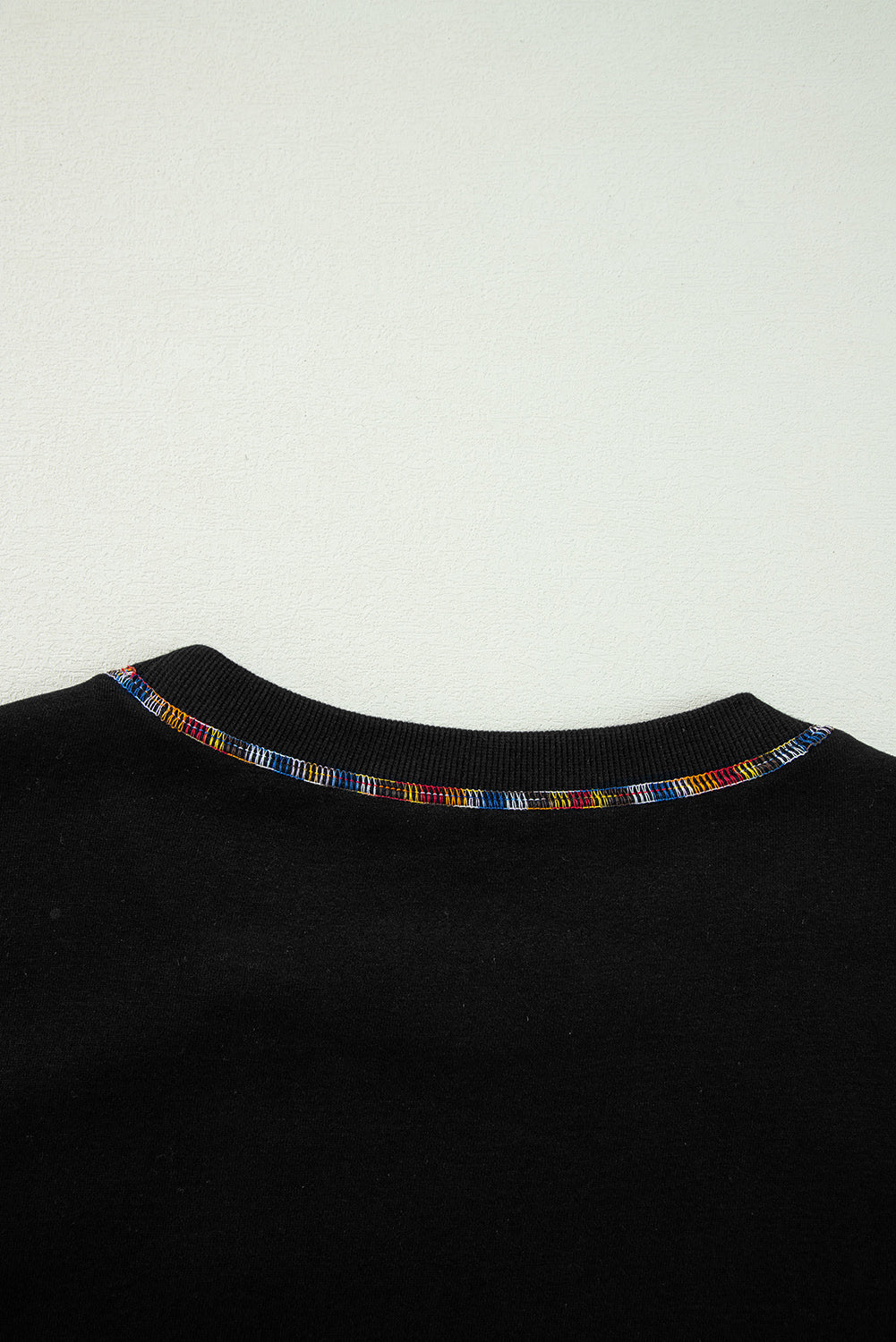 Schwarzes Pullover-Sweatshirt mit überschnittener Schulter und kontrastierendem Regenbogenbesatz