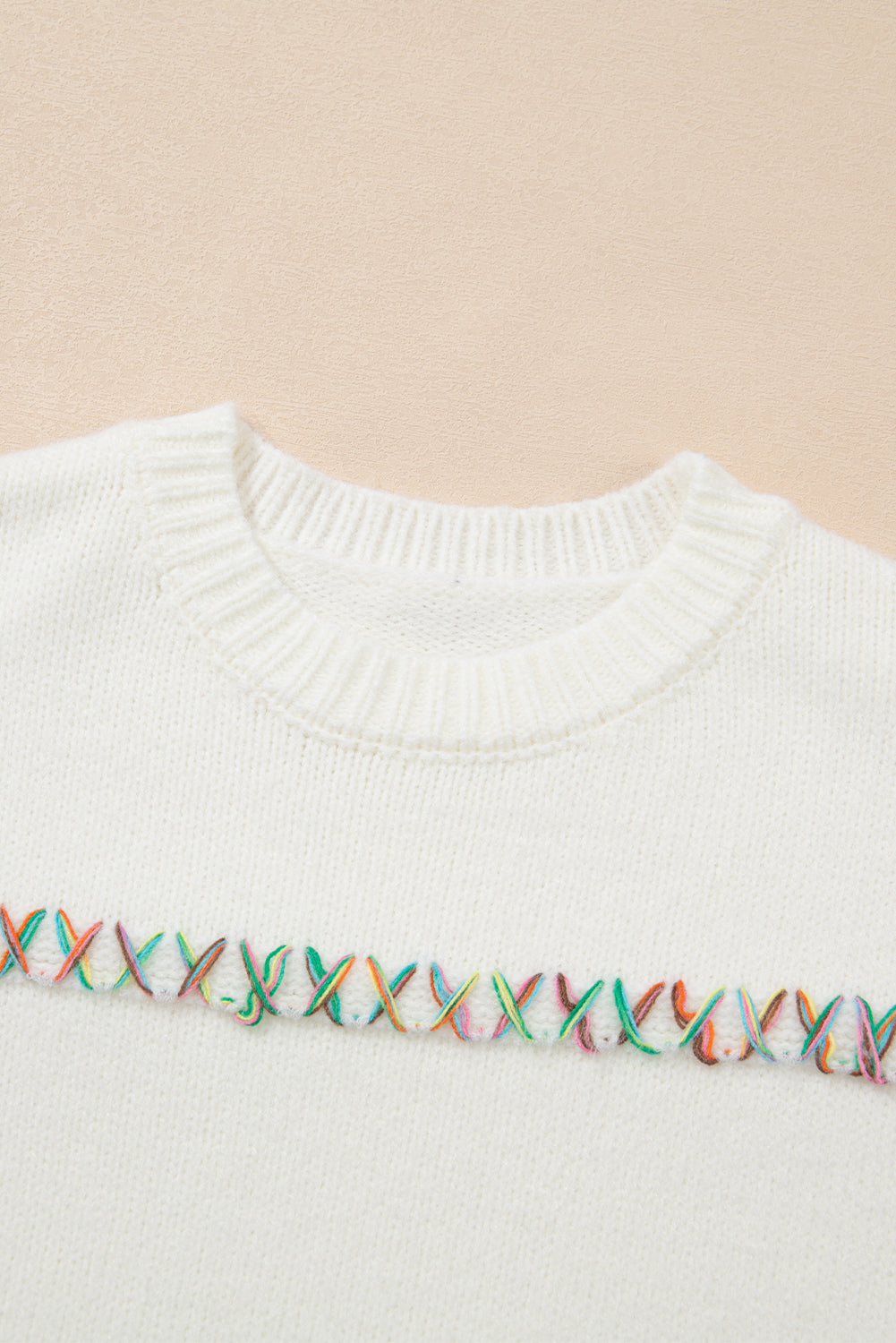 Weißer Pullover mit bunten Kreuzstichen und überschnittenen Schultern