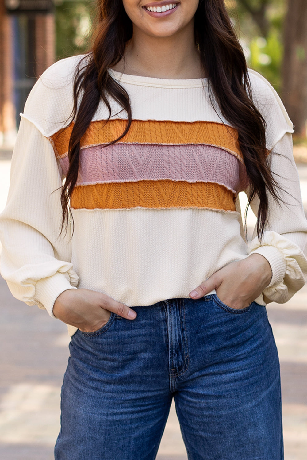 Weißes Stricktop mit Patchwork-Muster und sichtbaren Nähten sowie langen Ärmeln