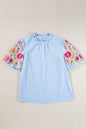 Hellblaue Bluse mit Puffärmeln und Blumenstickerei im Gingham-Stil