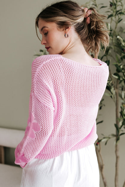Hellrosa Strickpullover mit großer Blume und tief angesetzter Schulterpartie