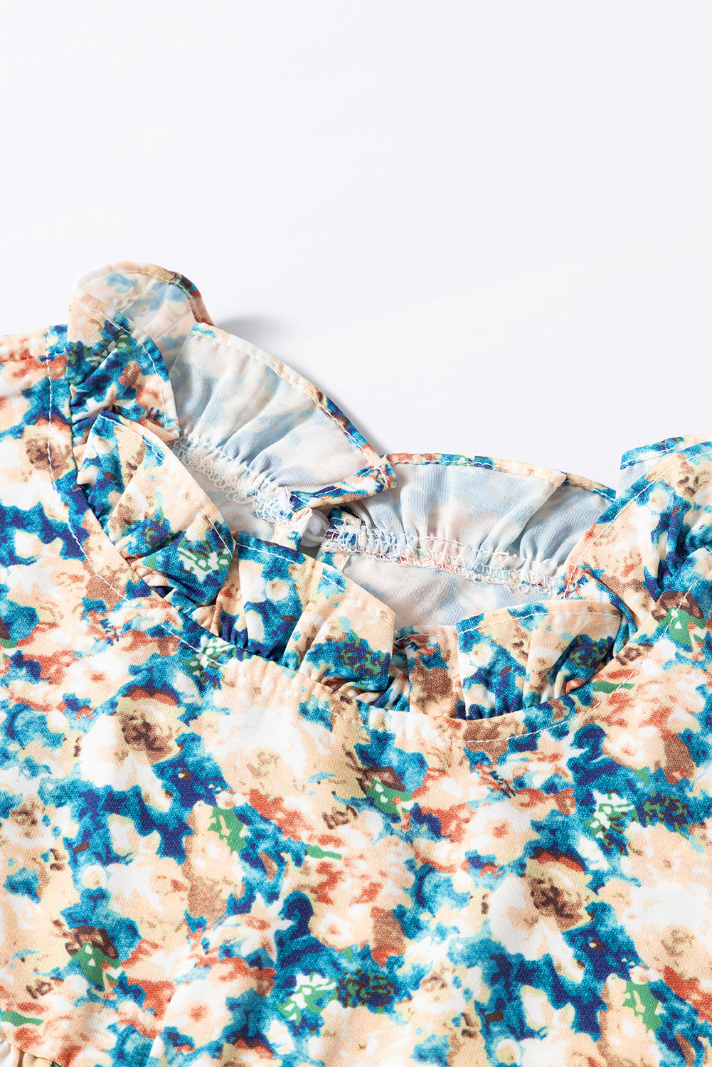 Himmelblaue Bluse mit Blumenmuster, Rüschen und Stehkragen sowie Puffärmeln