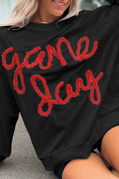 Schwarzes Lametta-Sweatshirt mit Game Day-Grafik und überschnittener Schulter
