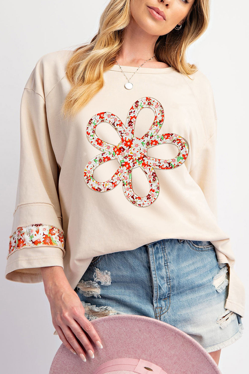 Beiges Oberteil mit Blumen-Patch-Grafik, sichtbaren Nähten und weiten Ärmeln