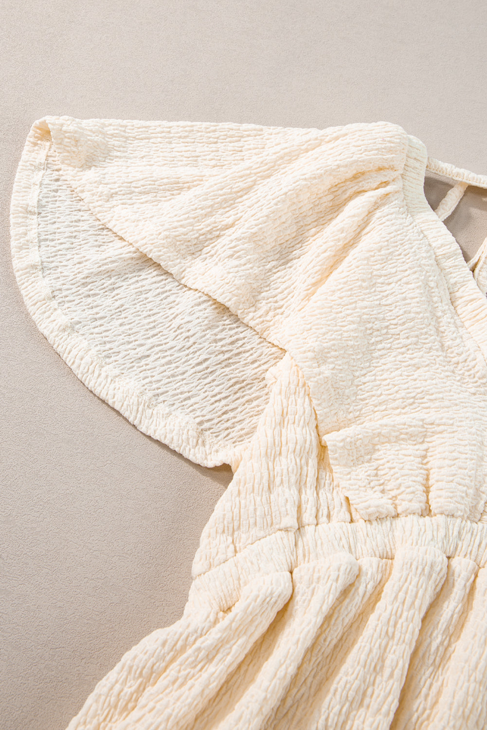 Beiges strukturiertes Minikleid mit tiefem V-Ausschnitt und Cut-Out auf der Rückseite