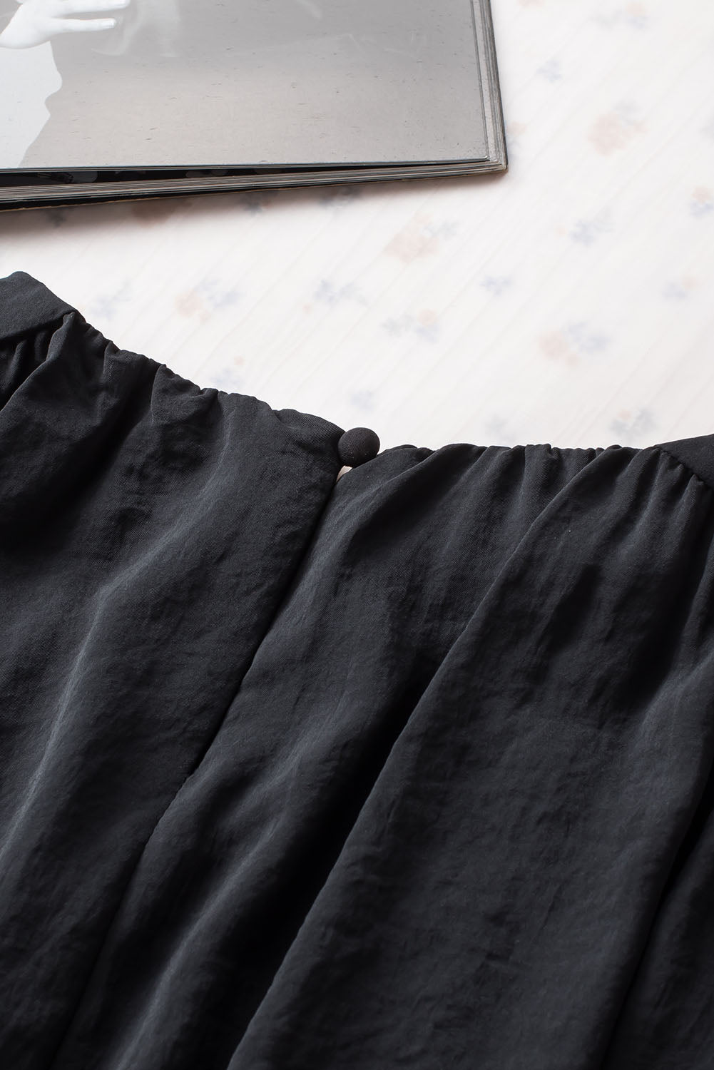 Schwarze, plissierte, lockere Bluse mit gepolsterten Schultern und geknöpften Manschetten
