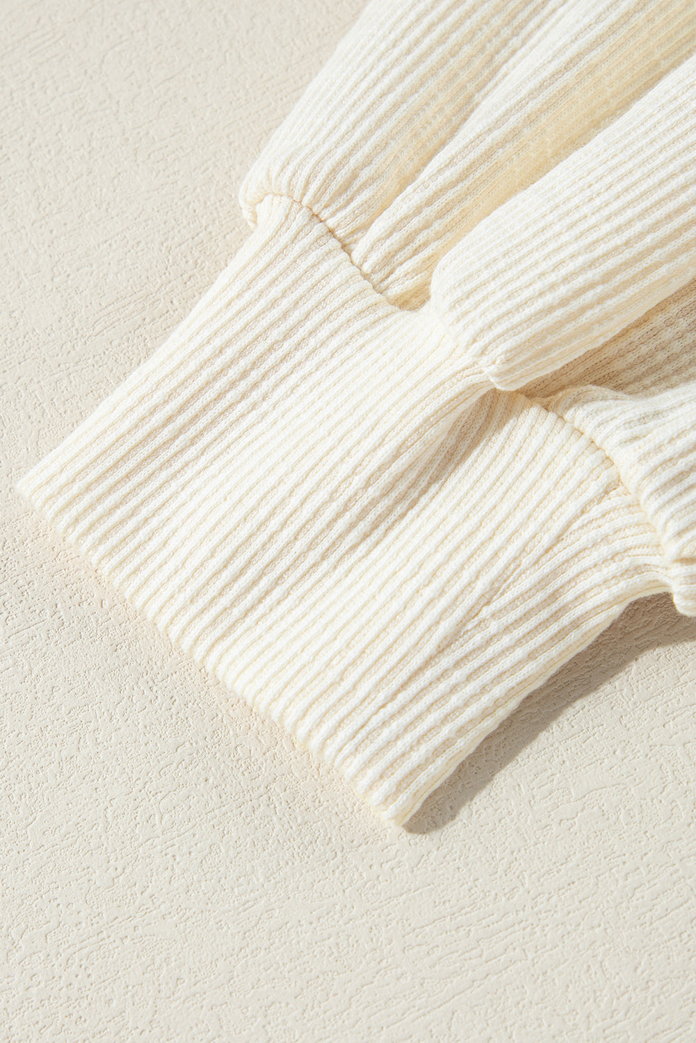 Beiges Pullover-Oberteil aus strukturiertem Strick mit sichtbaren Nähten und V-Ausschnitt
