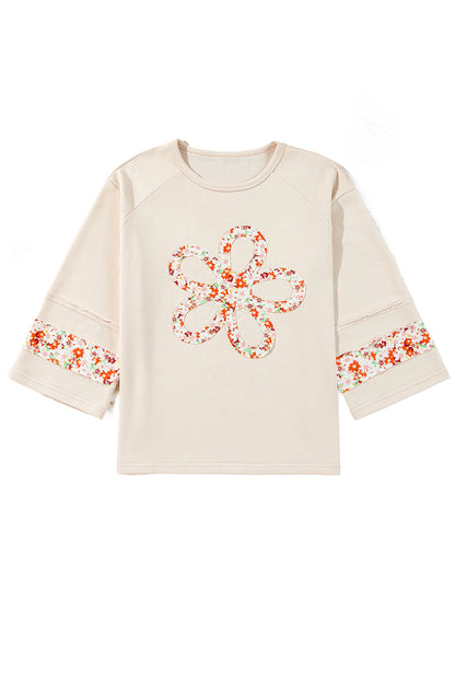 Beiges Oberteil mit Blumen-Patch-Grafik, sichtbaren Nähten und weiten Ärmeln