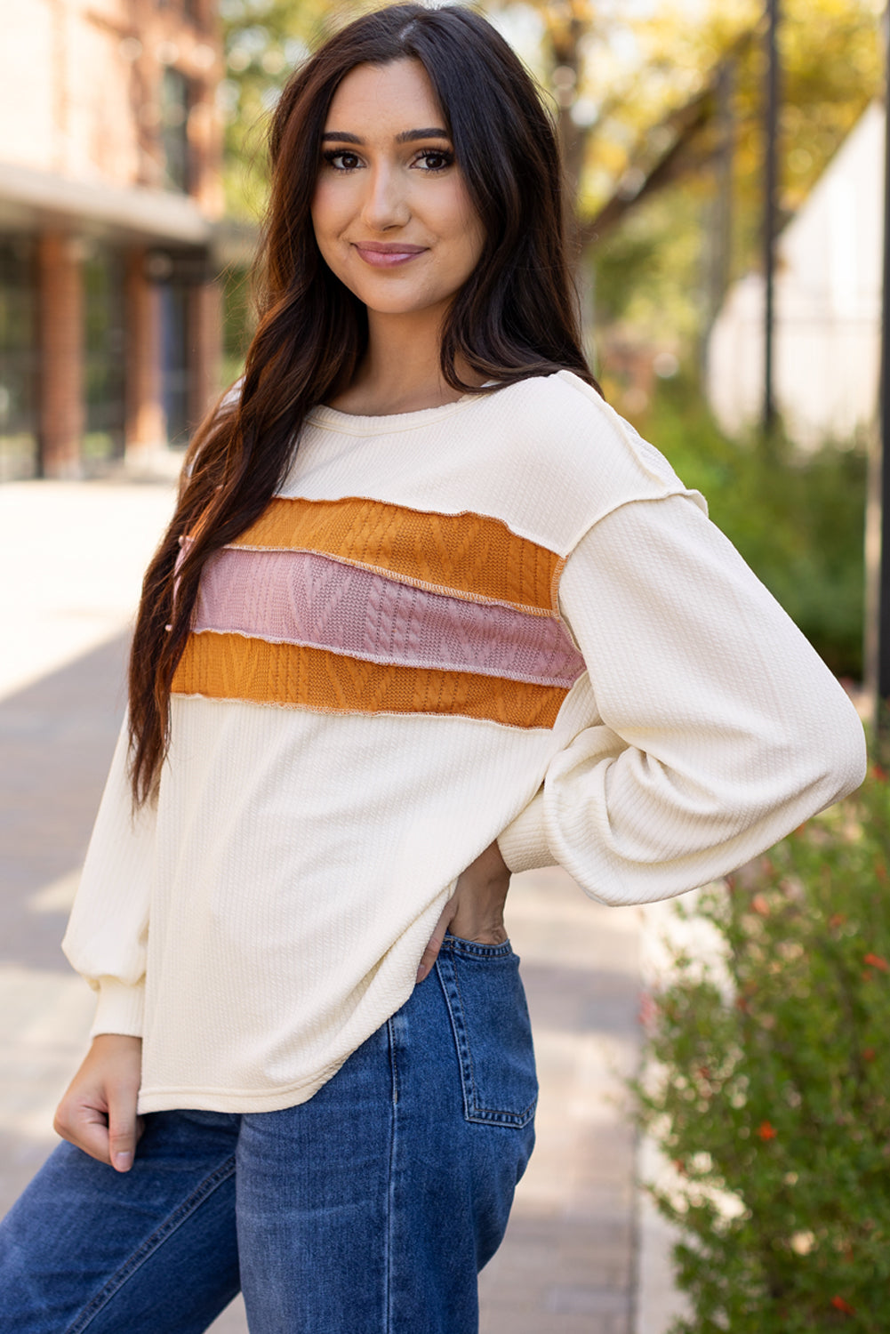 Weißes Stricktop mit Patchwork-Muster und sichtbaren Nähten sowie langen Ärmeln