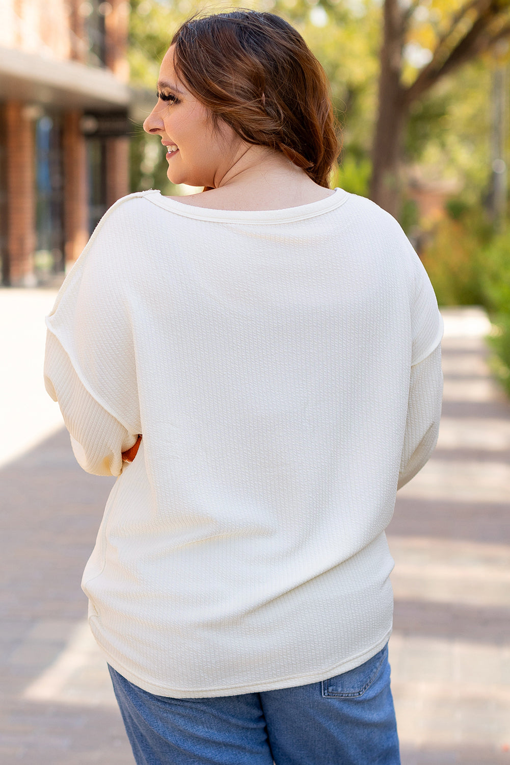 Weißes Stricktop mit Patchwork-Muster und sichtbaren Nähten sowie langen Ärmeln