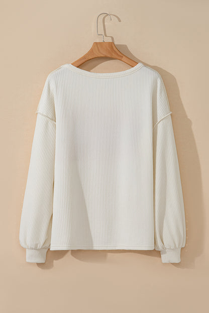 Weißes Stricktop mit Patchwork-Muster und sichtbaren Nähten sowie langen Ärmeln