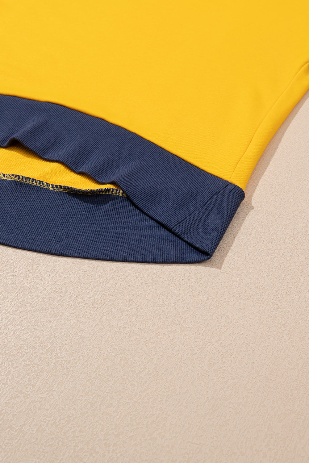 Gelbes Sweatshirt mit Farbblockdesign und Daumenlöchern an den Ärmeln sowie überschnittener Schulter