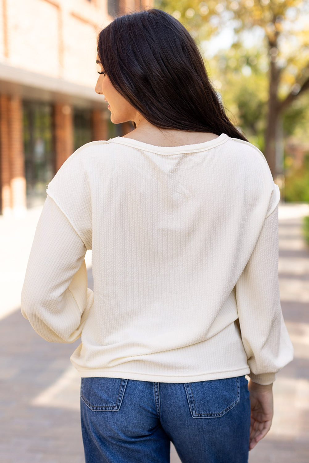 Weißes Stricktop mit Patchwork-Muster und sichtbaren Nähten sowie langen Ärmeln