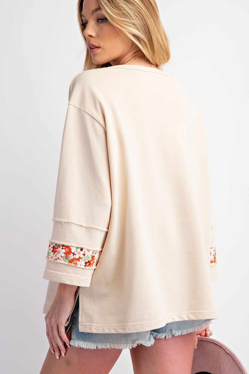 Beiges Oberteil mit Blumen-Patch-Grafik, sichtbaren Nähten und weiten Ärmeln