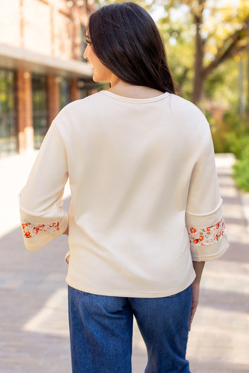Beiges Oberteil mit Blumen-Patch-Grafik, sichtbaren Nähten und weiten Ärmeln