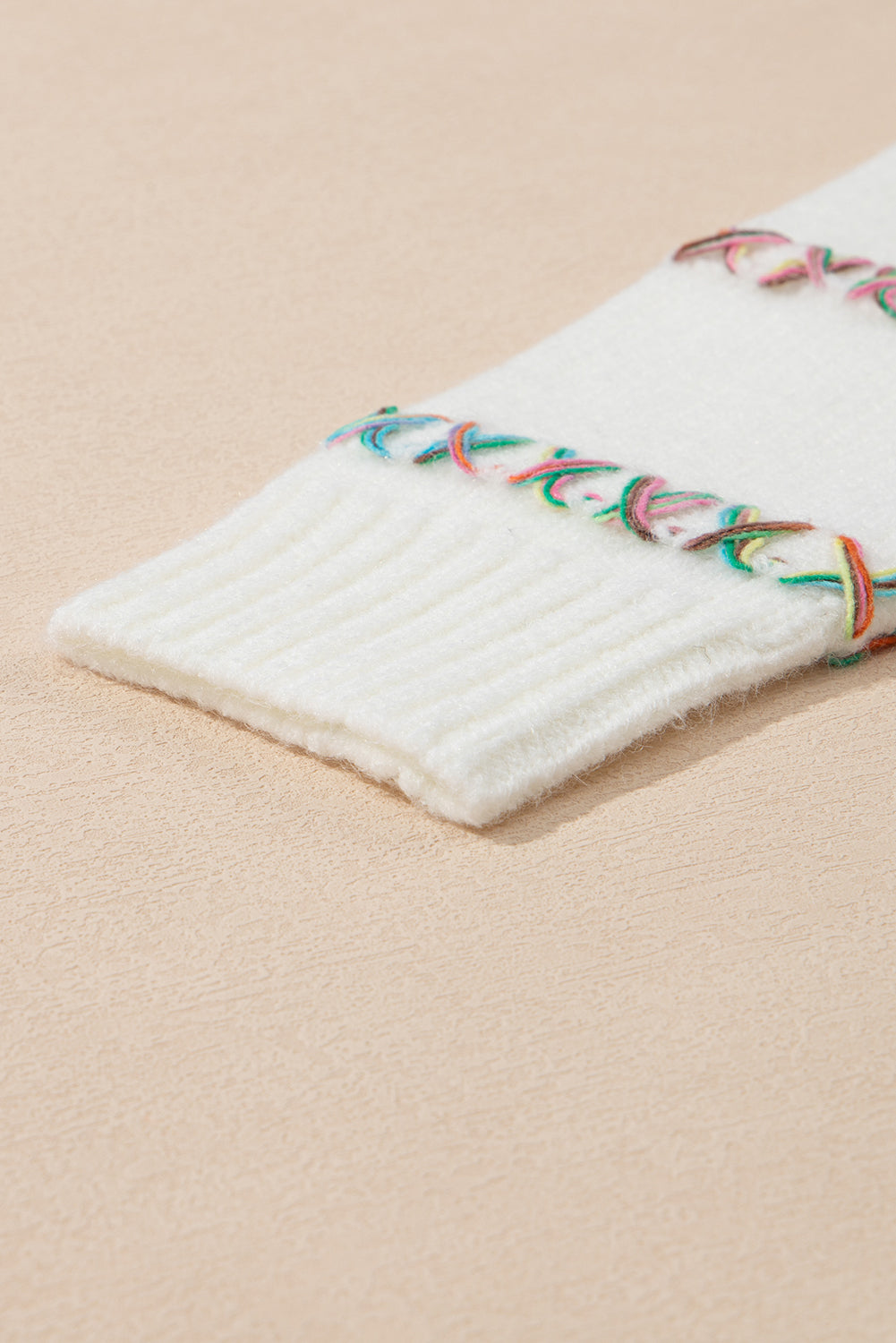 Weißer Pullover mit bunten Kreuzstichen und überschnittenen Schultern