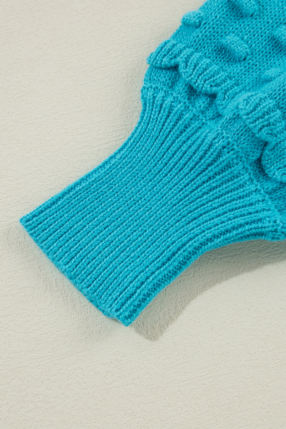 Türkisfarbener Pullover mit gerüschten Ösenärmeln