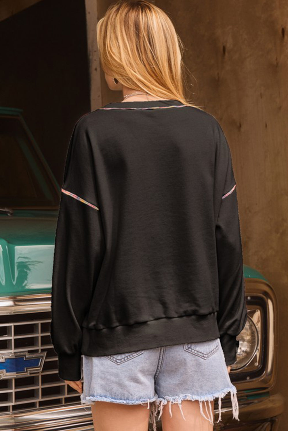Schwarzes Pullover-Sweatshirt mit überschnittener Schulter und kontrastierendem Regenbogenbesatz