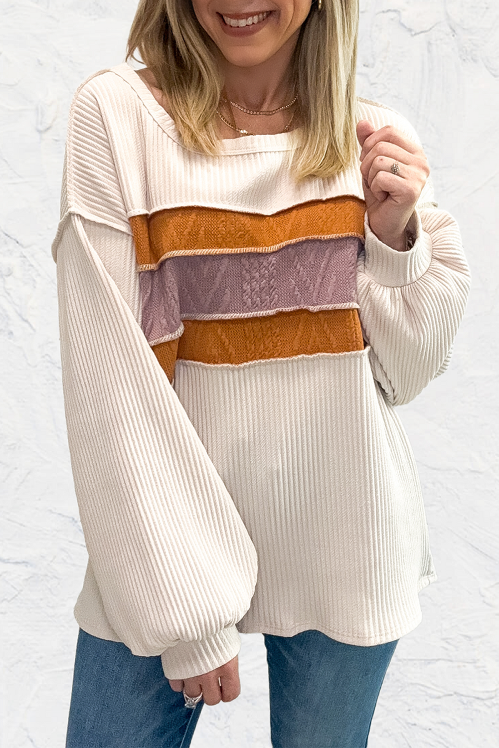 Weißes Stricktop mit Patchwork-Muster und sichtbaren Nähten sowie langen Ärmeln