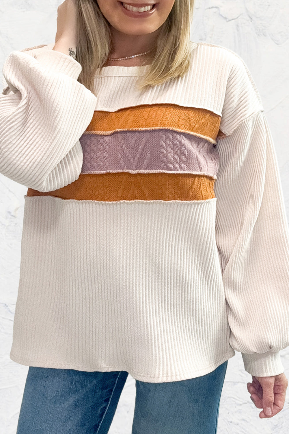 Weißes Stricktop mit Patchwork-Muster und sichtbaren Nähten sowie langen Ärmeln