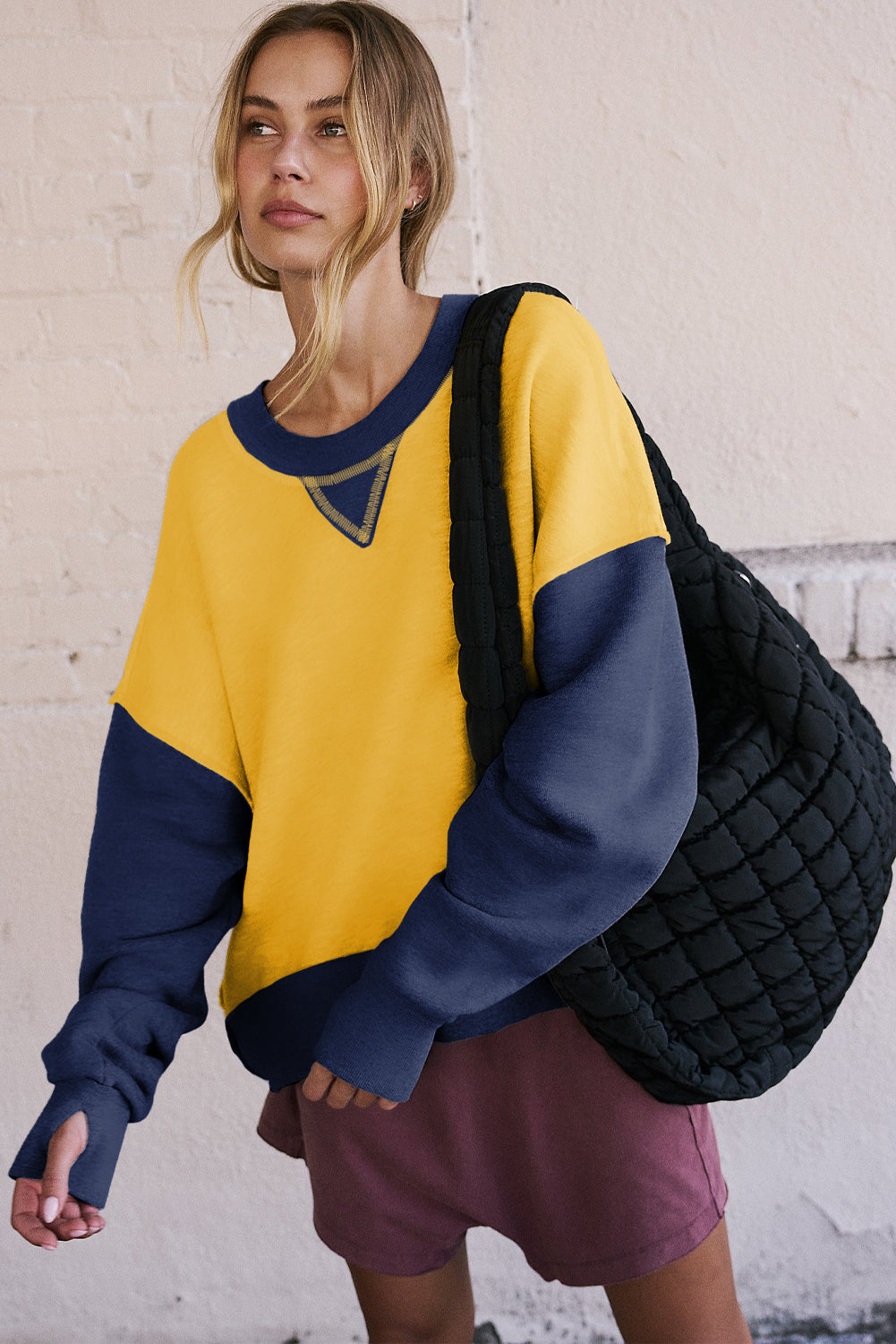 Gelbes Sweatshirt mit Farbblockdesign und Daumenlöchern an den Ärmeln sowie überschnittener Schulter